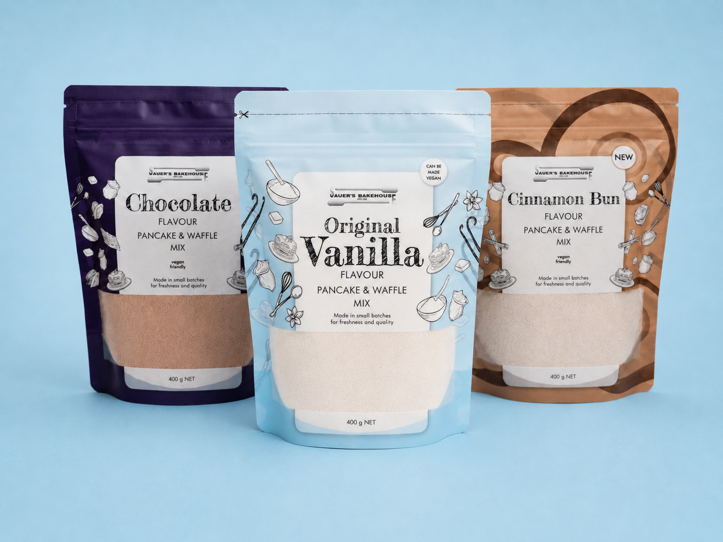 Three packages of pancake and waffle mix with different flavors on a blue background