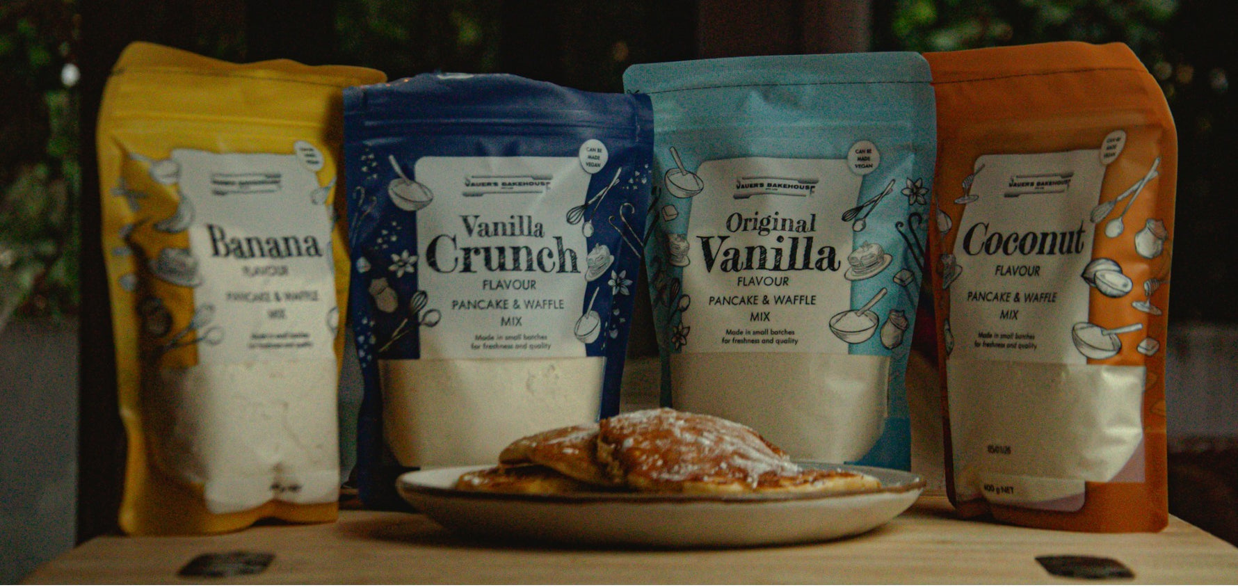 Four packages of pancake mix with a plate of pancakes in the foreground.
